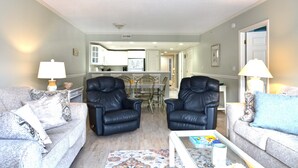 A living room with two black leather chairs, a grey sofa, and a white coffee table.