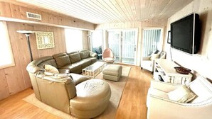 A cozy living room with a sectional sofa, a white armchair, and a television mounted on the wall. - Beautiful, oceanfront 5 bedroom townhome! (Ocean City)