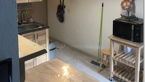 Une cuisine compacte avec des meubles en bois, un évier, un four à micro-ondes et un luminaire rouge suspendu.