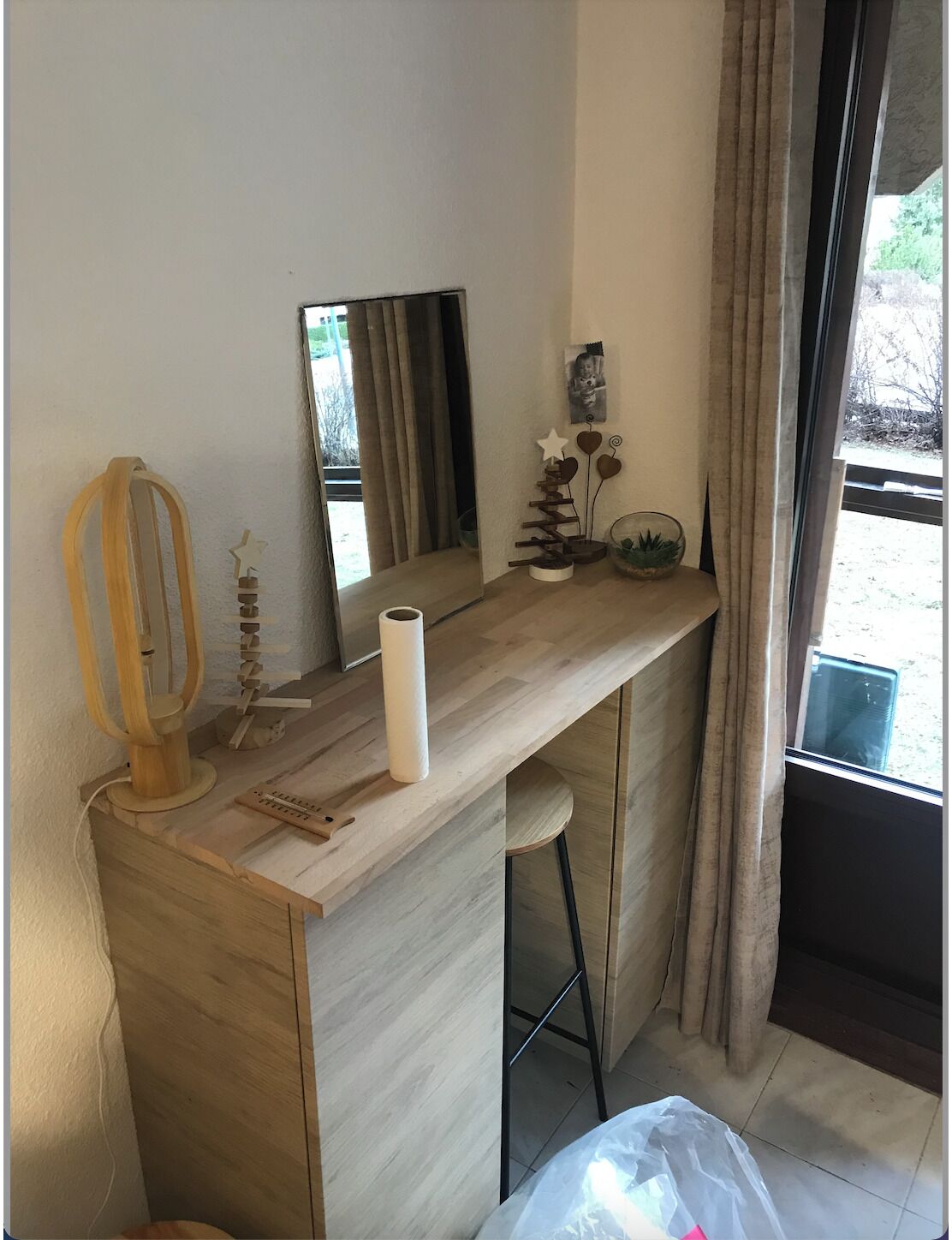 Une chambre moderne avec un bureau en bois, un miroir et une fenêtre avec des rideaux.