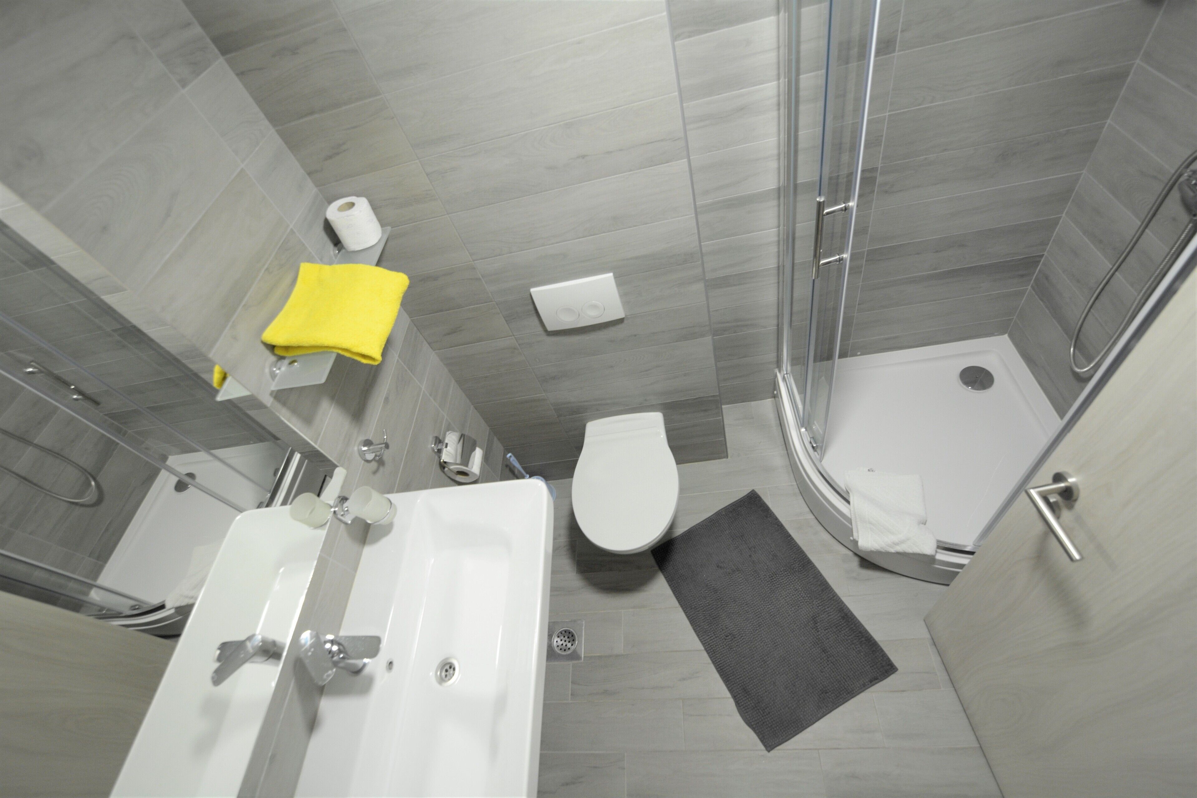 Een moderne badkamer met douche, toilet en wastafel.