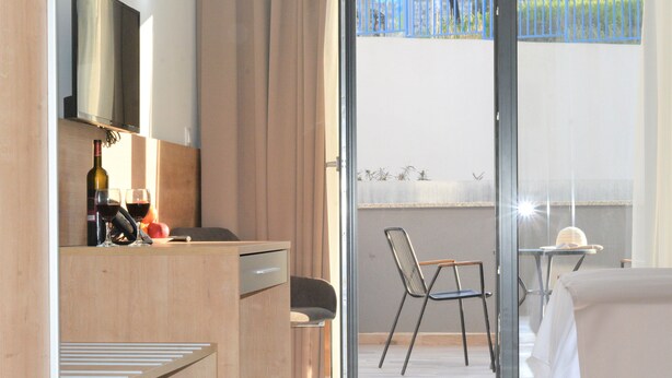 A hotel room with a wooden desk, a chair, a dining table with a chair, and a balcony with a view of the outside. - B&B Boutique Eluize Dubrovnik (Dubrovnik)