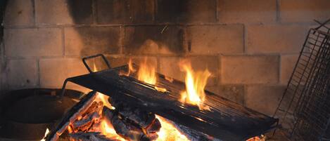 A fireplace with burning logs and a metal grate.