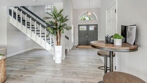 Een modern interieur met een trap, een ronde houten tafel en een potplant.
