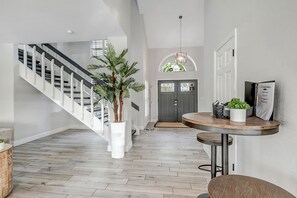 Ein modernes Interieur mit Treppe, einem runden Holztisch und einer Topfpflanze.