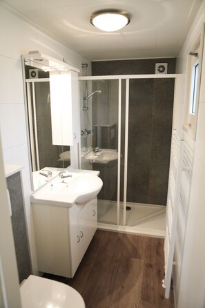 Une salle de bain moderne avec une douche à parois de verre, un lavabo blanc et un miroir au-dessus.