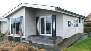 Una casa moderna de dos pisos con techo plano, ventanas amplias y un porche cubierto.