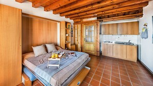 Ein gemütliches Schlafzimmer mit Bett, Nachttisch und einer kleinen Küchenzeile.