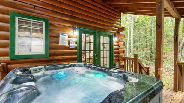 Une cabane en bois avec un jacuzzi sur une véranda.