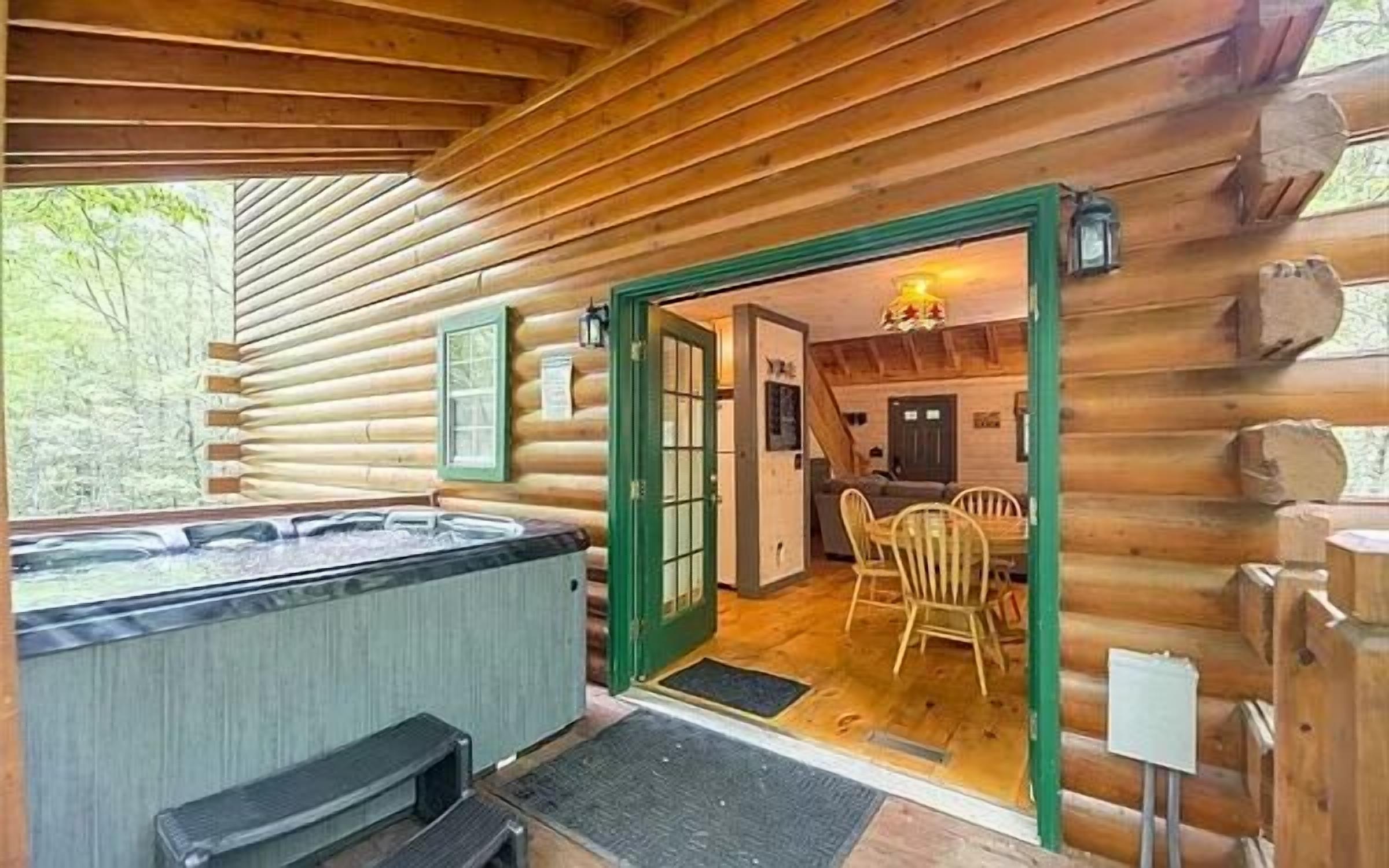 A log cabin with a hot tub, wooden interior, and a dining area.
