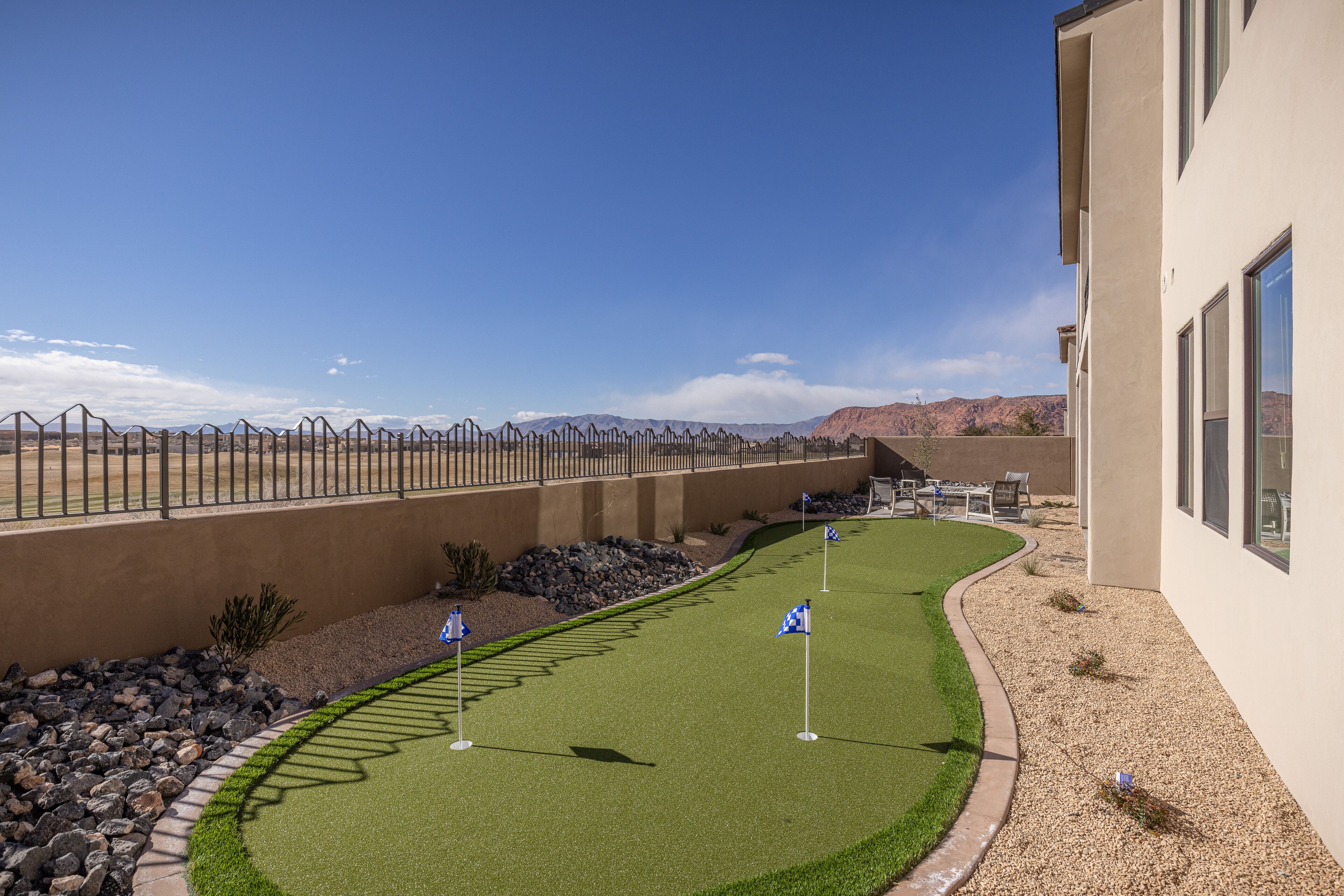 Un parcours de golf avec un ciel dégagé, une zone délimitée par une clôture et un bâtiment doté de grandes fenêtres.
