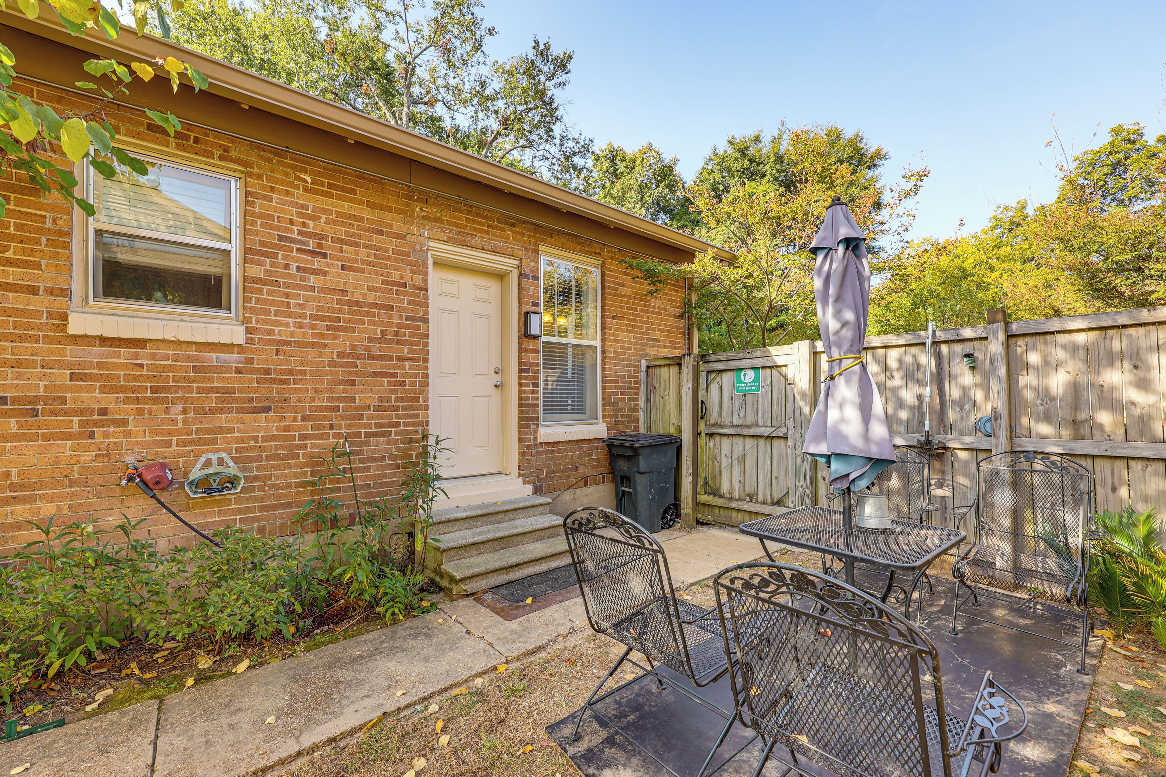 A brick house with a front door, a window, and a patio area with metal chairs and a table.