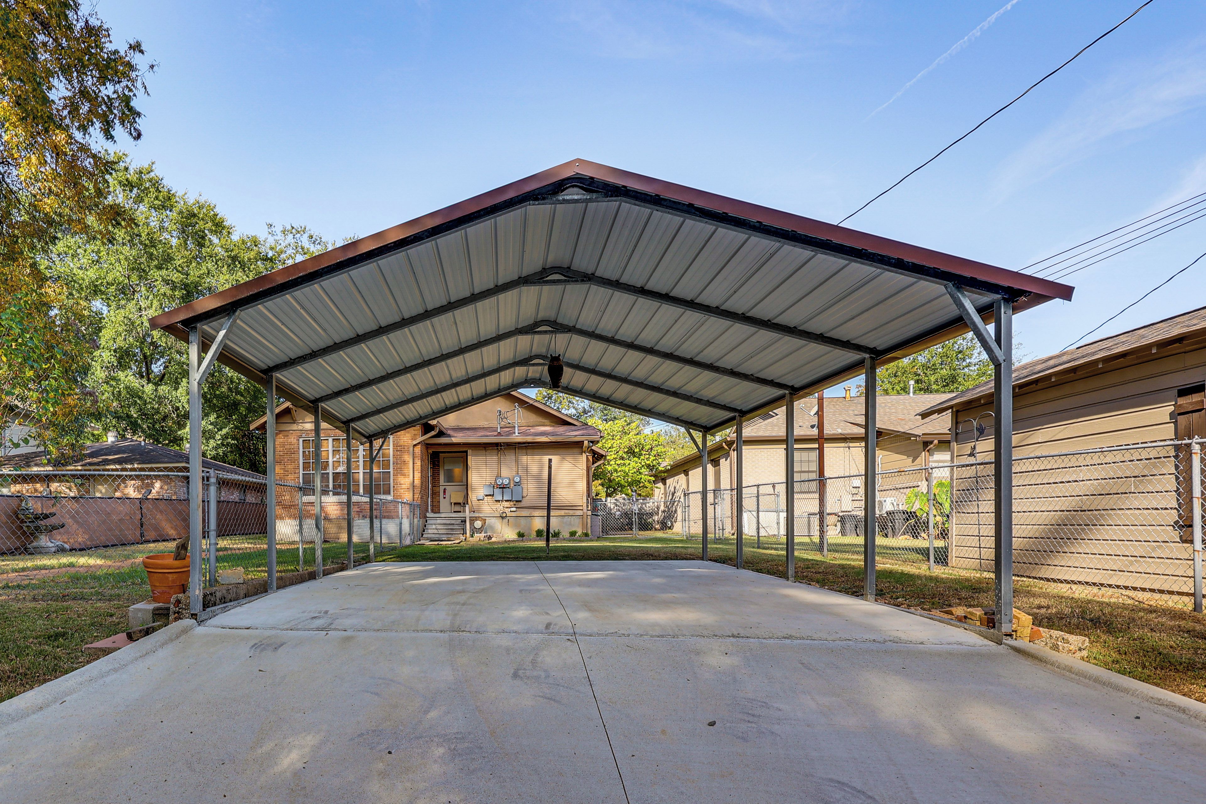 A covered outdoor area with a metal roof, concrete floor, and metal fencing.