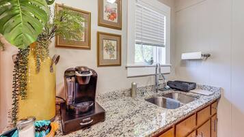 A kitchen with a coffee maker, sink, and decorative plants.