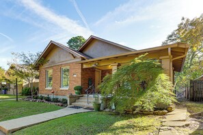 A two-story house with a covered porch, brick exterior, and a small front yard with a pathway leading to the entrance. - Pet-Friendly Home w/ Fenced Yard in Texarkana (Texarkana)