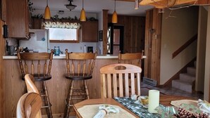 Un intérieur en bois avec une table à manger dressée pour quatre personnes, entourée de chaises en bois.