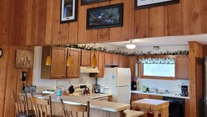 Une cuisine rustique aux murs en bois, avec un îlot central doté de tabourets de bar et des tableaux encadrés accrochés au mur.