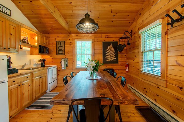 L'intérieur d'un chalet en bois comprend une cuisine, un coin repas et de grandes fenêtres.