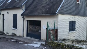 Ein zweigeschossiges Haus mit geneigtem Dach, einer kleinen Veranda und einem Maschendrahtzaun.