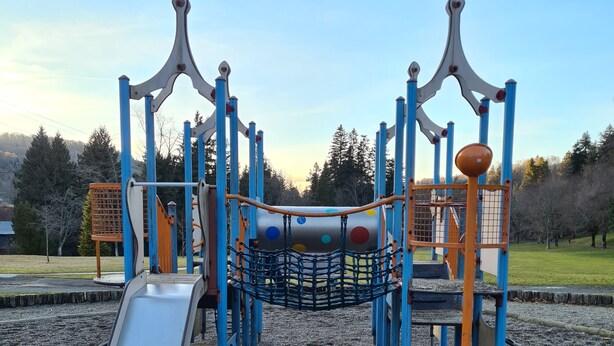 Ein Spielplatz mit Rutsche, Klettergerüsten und einer Netzbrücke.