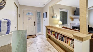 A hallway with a bookshelf, a door, and a mirror. - 137 Beachwalk Villa Steps To The Beach (Hilton Head Island)