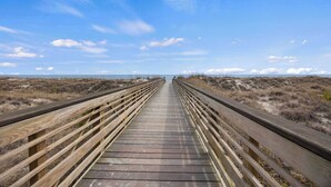 Un muelle de madera que conduce a una playa con cielo despejado.