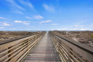 Una passerella in legno che conduce a una spiaggia sotto un cielo sereno.