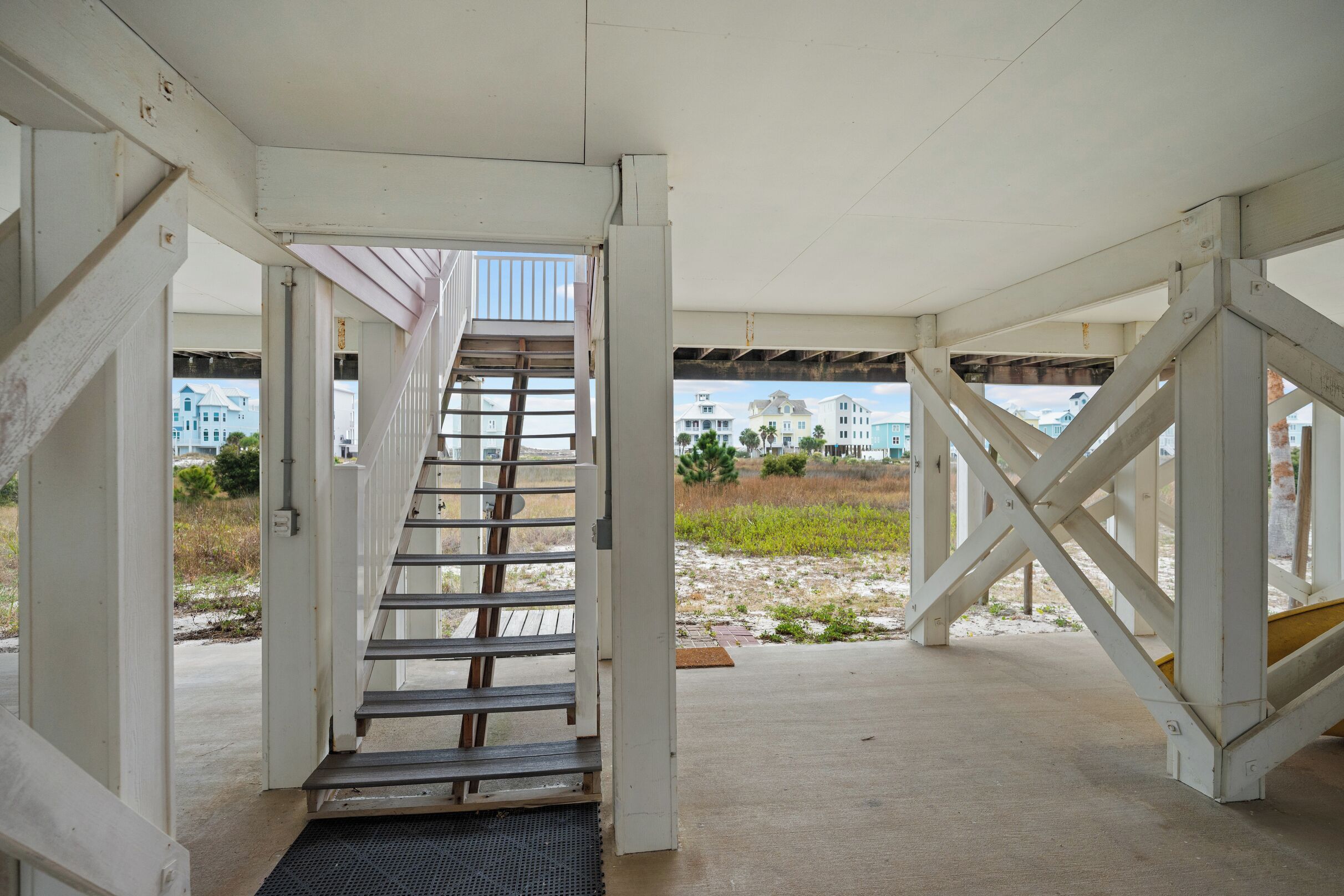 Una escalera techada al aire libre que lleva a un edificio, con vistas a una playa y casas.