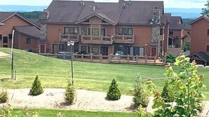 Un grand immeuble à étages, doté d’un balcon imposant, entouré d’une pelouse bien entretenue et de petits arbres.