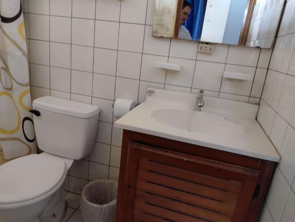 A bathroom with a toilet, sink, and mirror.
