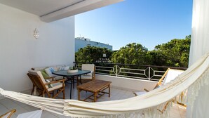 A balcony with a hammock, a table, chairs, and a view of trees and buildings. - Apartment Salgados Lounge - By D´alma Portuguesa (Albufeira)
