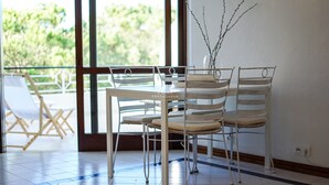 A dining area with a table and chairs, a vase with branches, and a view of greenery outside. - Apartment Salgados Lounge - By D´alma Portuguesa (Albufeira)