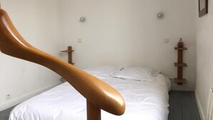 A bedroom with a wooden headboard, a bed with white bedding, and a small bedside table with a vase. - Charming Valentine fisherman's cottage, town center, close to train station and beach (Trouville-sur-Mer)