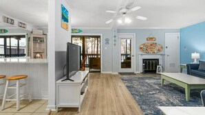 Ein Wohnzimmer mit Fernseher, Holzboden, Deckenventilator und blauer Wand.