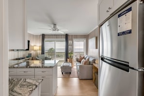 Uma cozinha moderna com bancada de mármore, ventilador de teto e geladeira com painel de acesso.