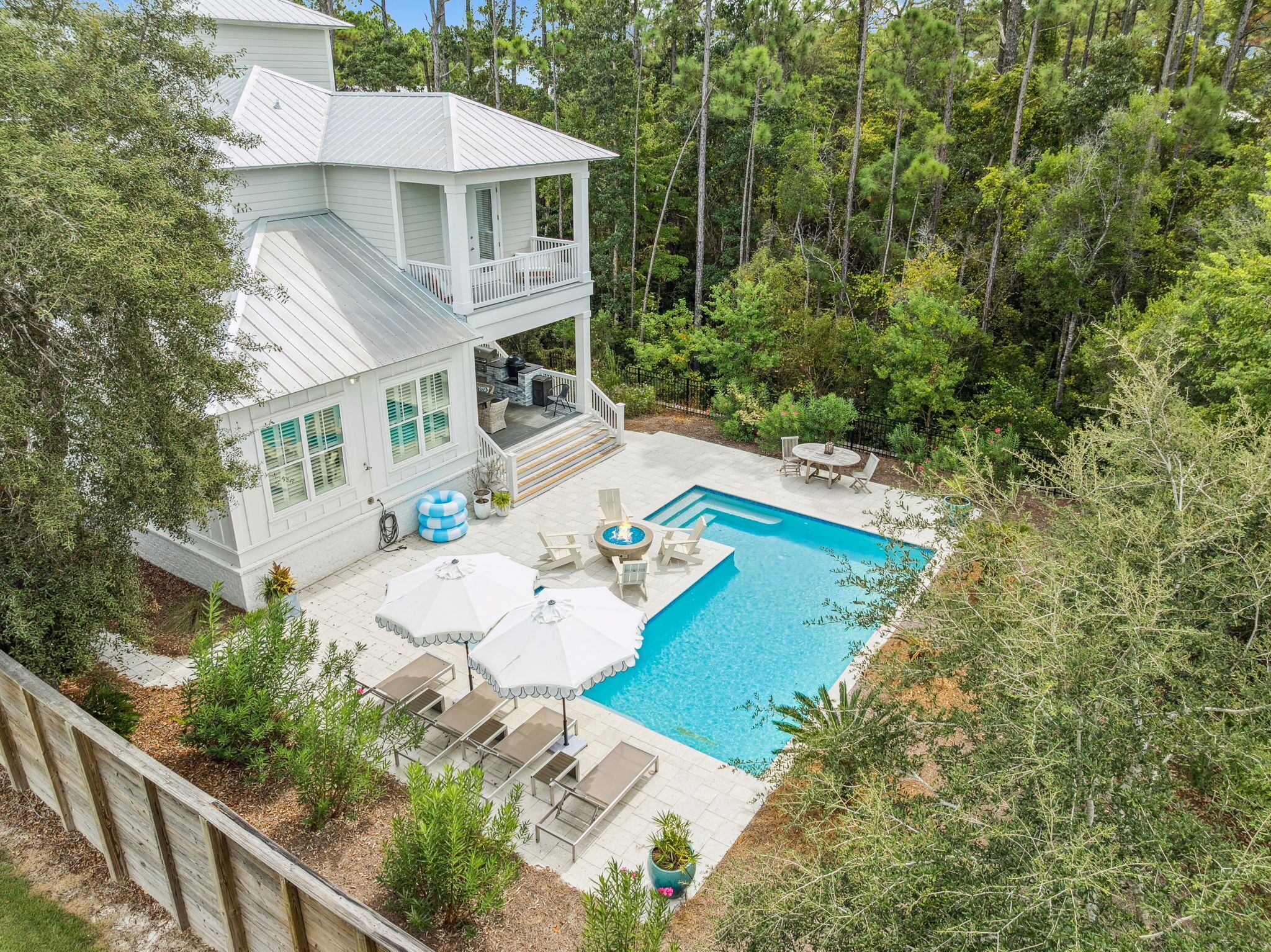 Une maison à deux étages avec une piscine, du mobilier d’extérieur et une terrasse.