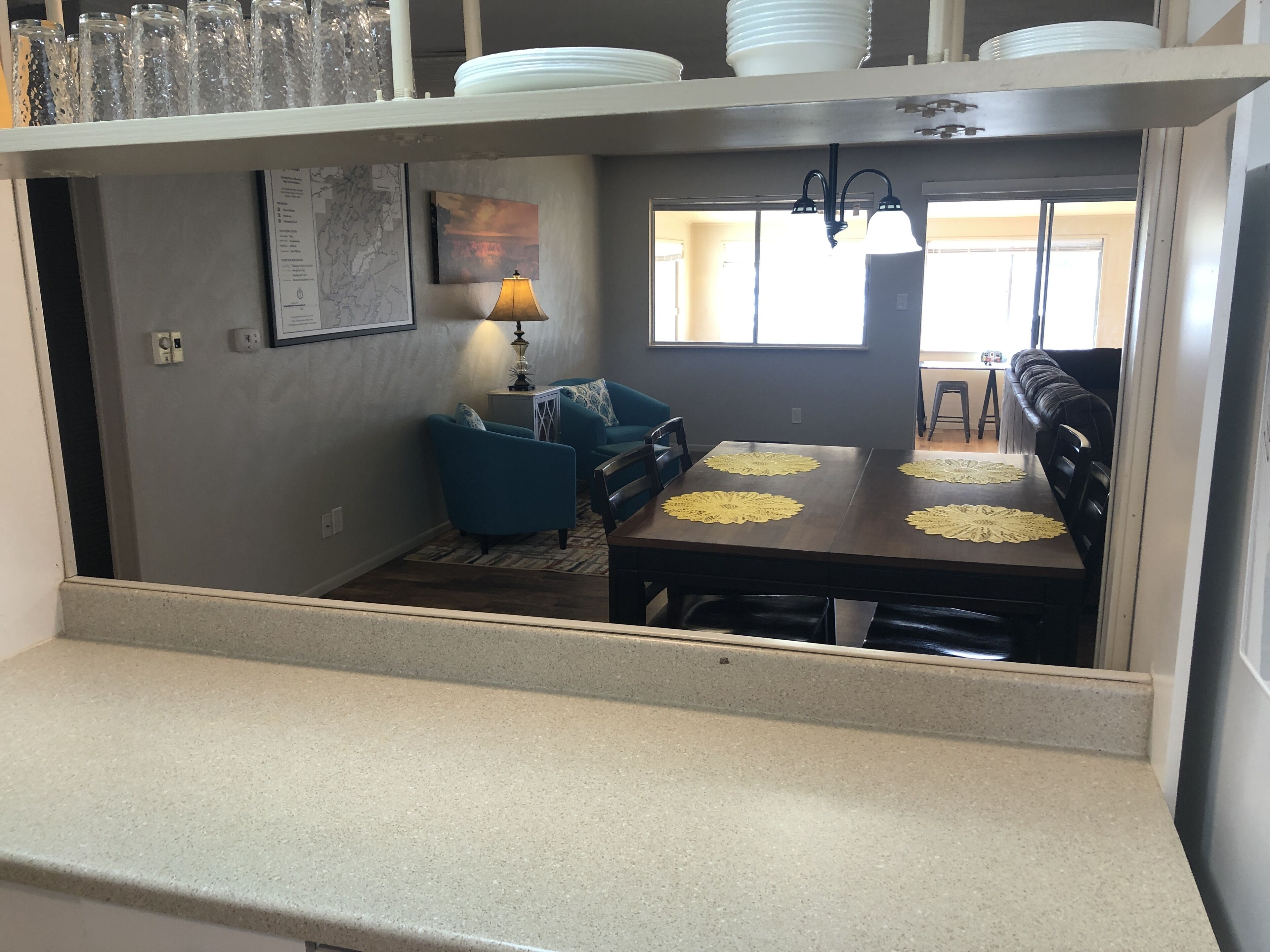 Un coin repas avec une table dressée pour quatre personnes, un canapé bleu et une lampe.