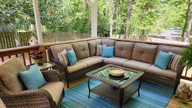 A covered patio with a sectional sofa, wicker chairs, and a coffee table.