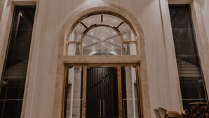 Un hall d’entrée spacieux avec un plafond haut, une grande porte en arc de cercle et un lustre.