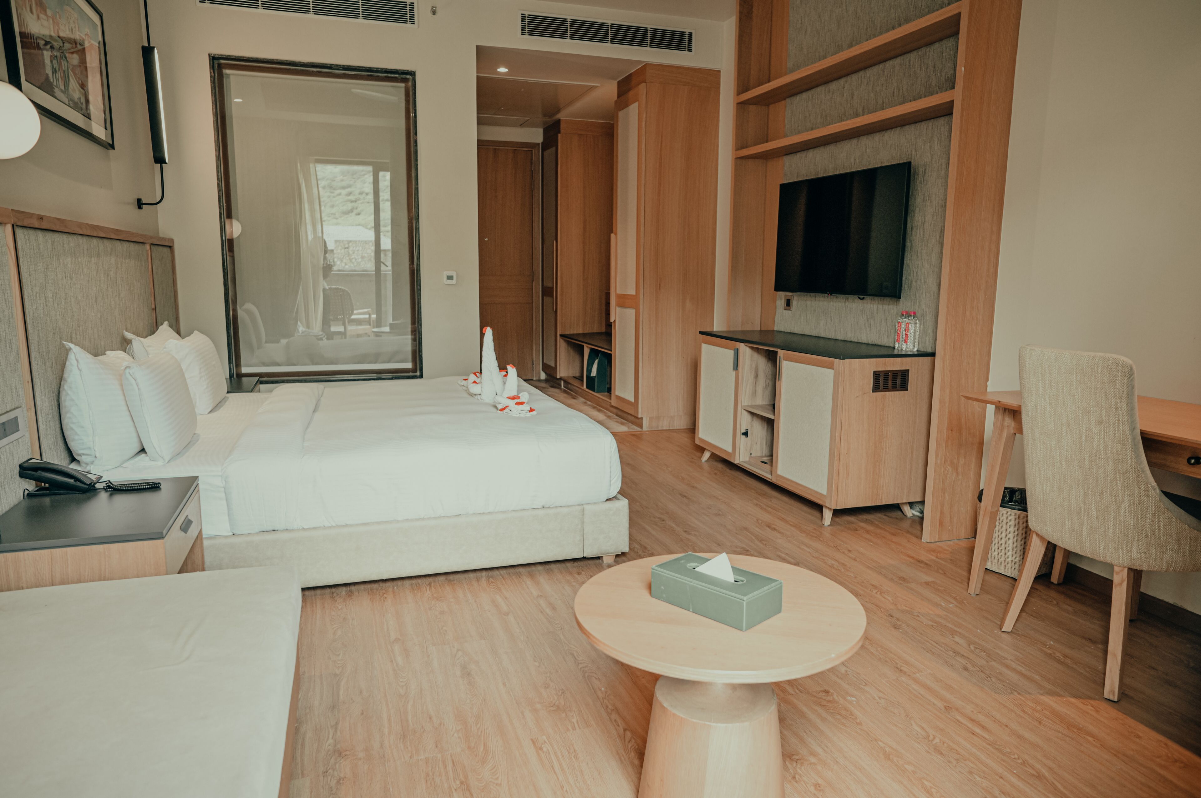 Camera d'albergo moderna con un letto, comodino, lampada e un tavolino rotondo con un portatovaglioli di carta.