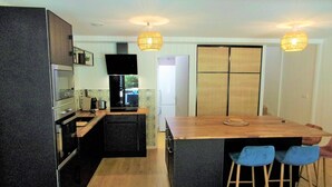 A modern kitchen with a central island, bar stools, and pendant lighting.