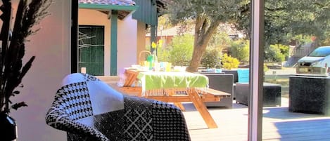A room with a large window, a patterned chair, and a table set outdoors with a green tablecloth.