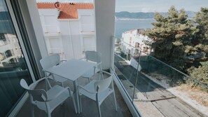 Enjoy breathtaking views of the coastline from this balcony, featuring a table and chairs.