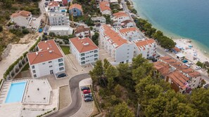 Enjoy a tranquil coastal retreat with apartment buildings and villas surrounded by lush greenery and a sandy beach.