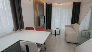 Relax in this stylish living space with a dining table, sofa, and flat-screen TV.