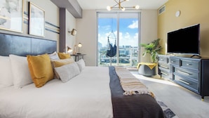 Een moderne hotelkamer met een groot bed, een televisie, stadszicht en een balkon.