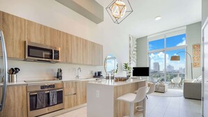 A modern kitchen with a built-in oven, microwave, and a large window offering a city view.