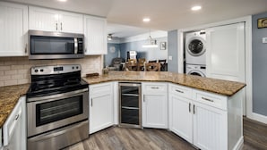 A kitchen with white cabinets, stainless steel appliances, a granite countertop, and a built-in oven.
