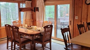 Un intérieur en bois avec une table et des chaises, de grandes fenêtres et une vue sur l’extérieur.