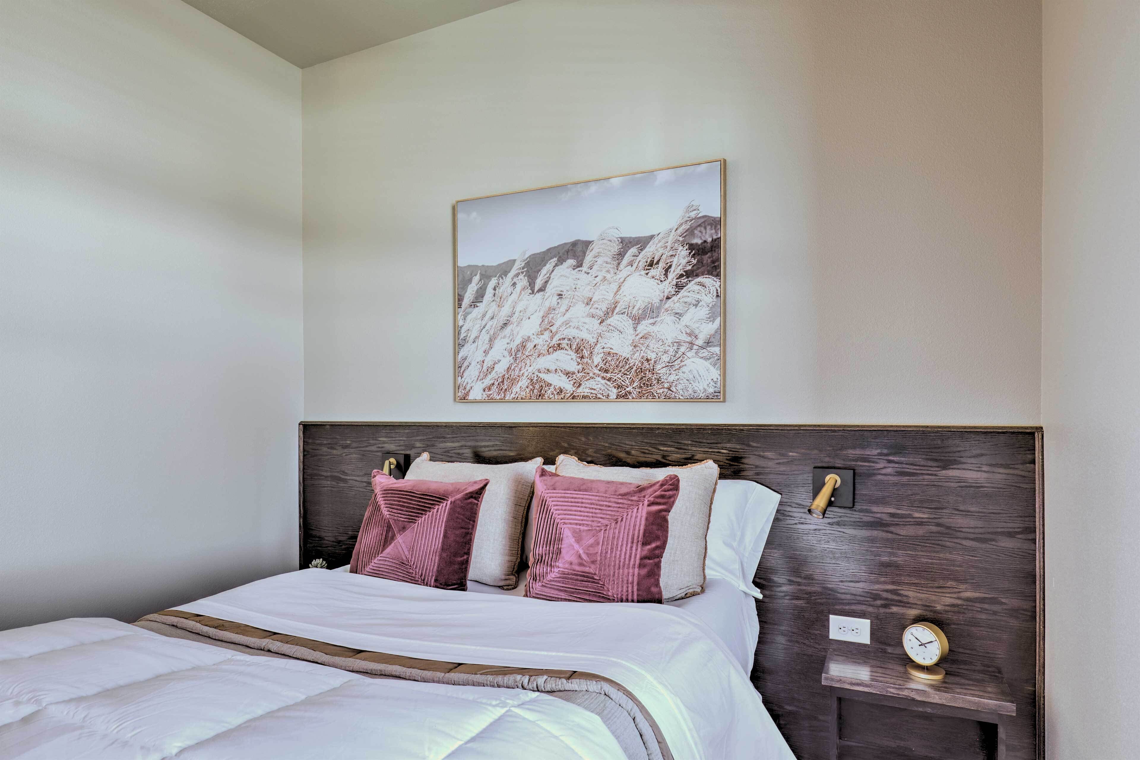 Un lit bien fait, avec une tête de lit en bois, deux oreillers roses et une couette blanche.